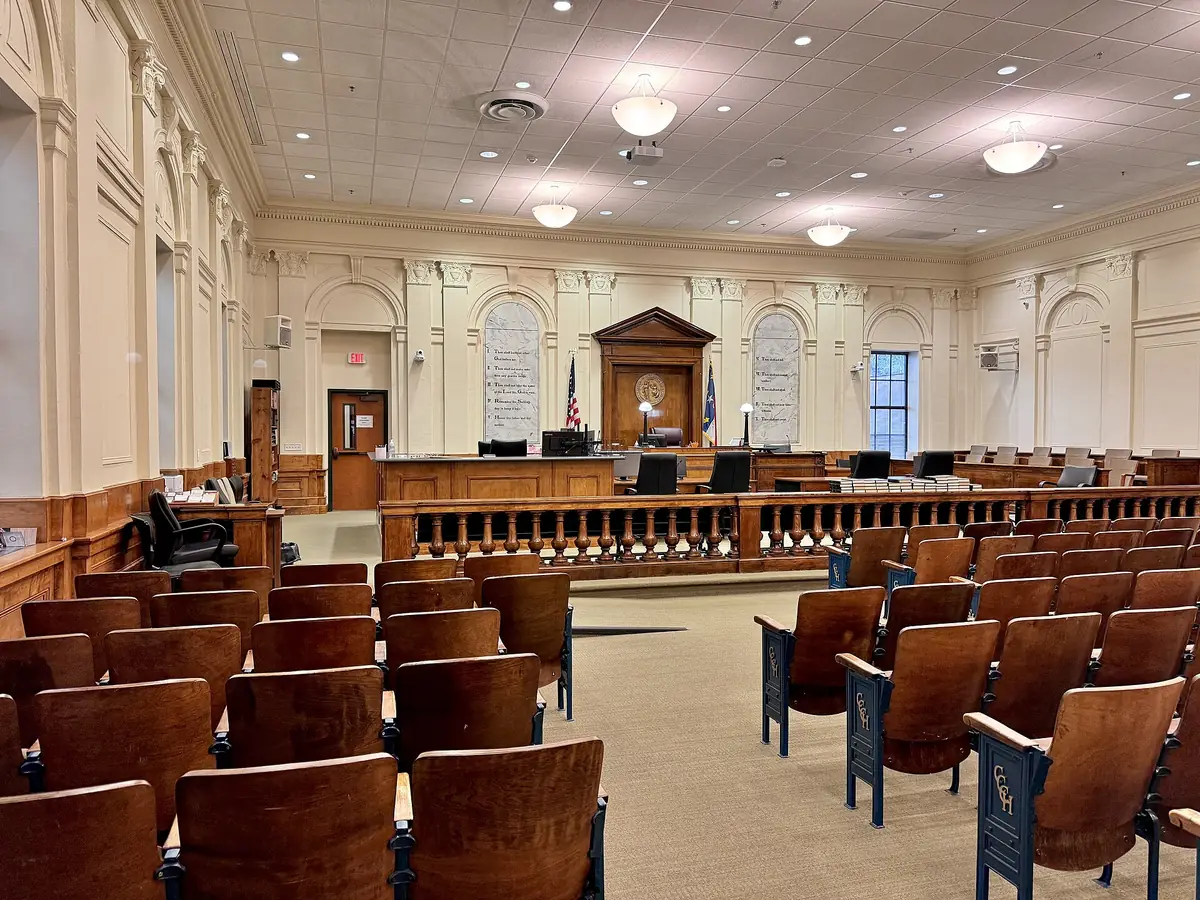 Historic courtroom with rows of wooden theater seats facing the judge's bench and paneled walls