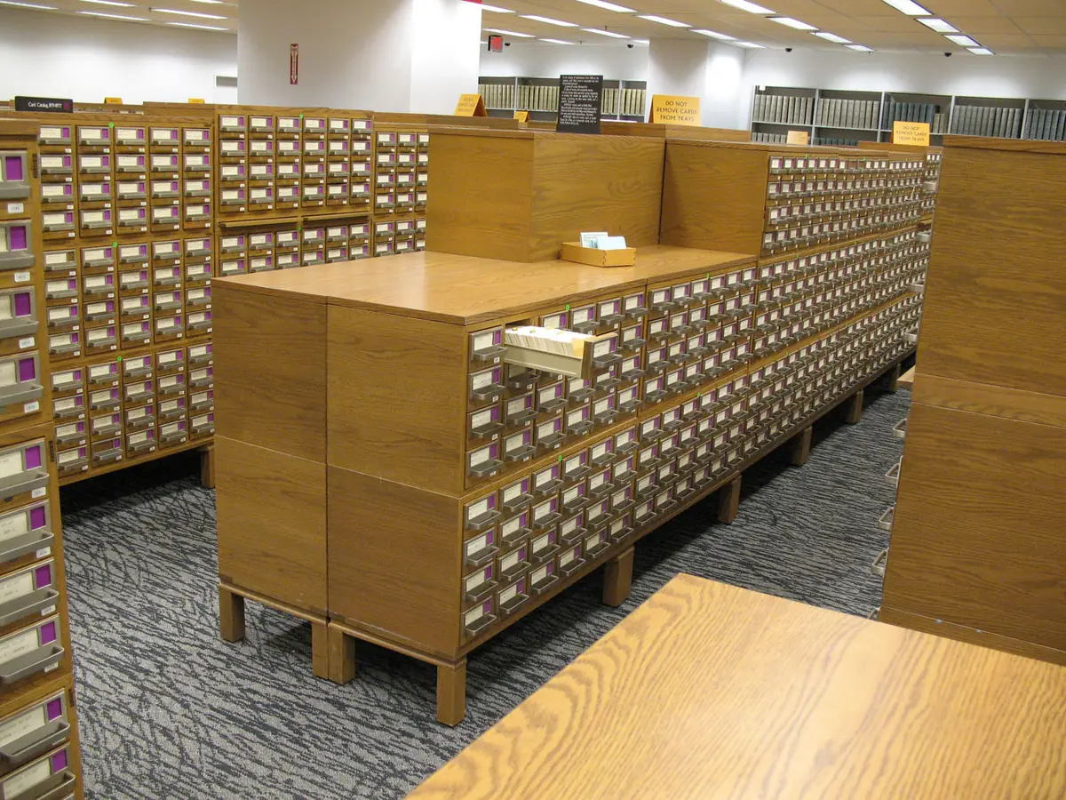 Long rows of wooden card catalog cabinets with small drawers in a library office