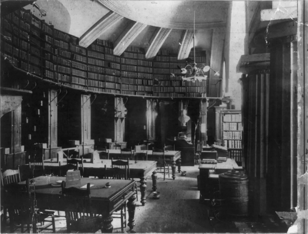 Historic black and white photo of a vaulted law library room in the U.S. Capitol lined with bookshelves and reading tables