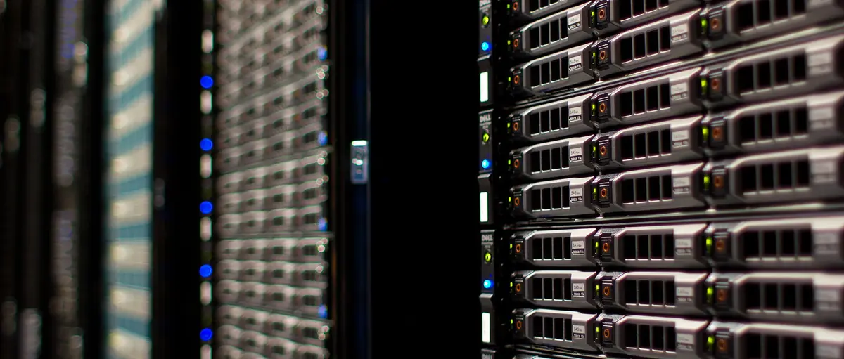 Rows of rack-mounted computer servers with small blue status lights in a data center